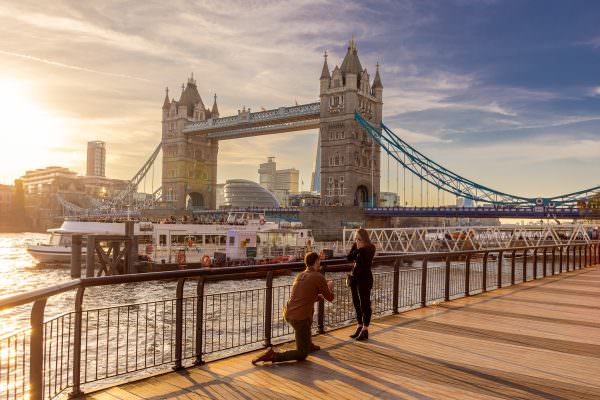 The moment of a marriage proposal with a view of Tower Bridge in the background.