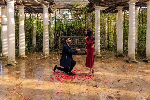 A surprise marriage proposal taking place beneath the historic, vine-covered walkways of The Hill Garden and Pergola.