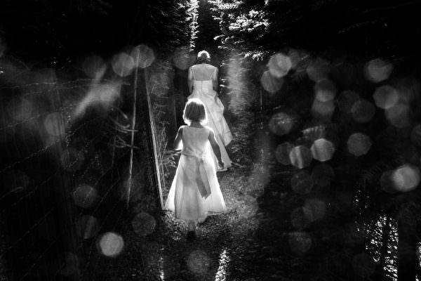 Bride and flower girl walking in the rays of sun in the garden