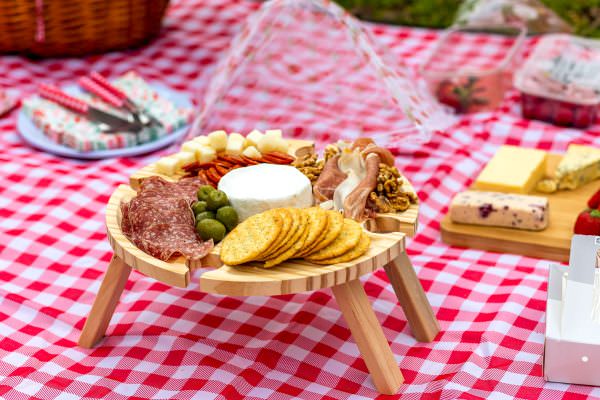 An elegant assortment of gourmet picnic food on a tray, including fine cheese, prosciutto, and salami, beautifully arranged for a surprise London marriage proposal.