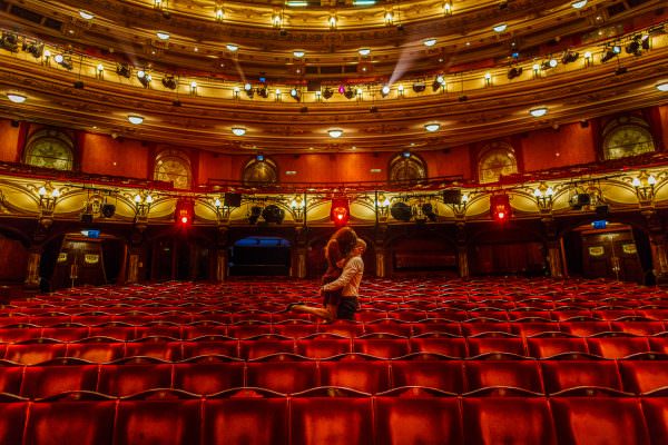 A newly engaged couple posing elegantly inside the London Coliseum after a secret proposal.